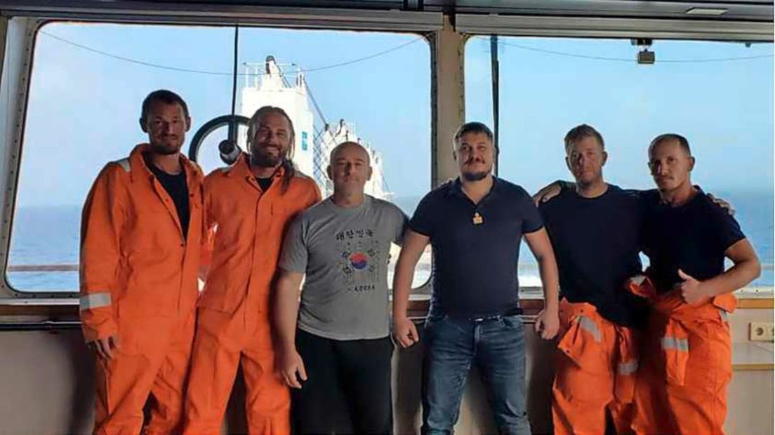 De vier Amerikaanse drenkelingen in oranje Hanzevast-overalls, met in het midden de kapitein en de chief officer van het schip