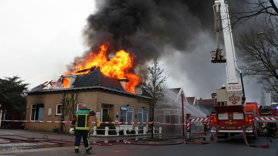 De vlammen slaan inmiddels uit het dak en er komt veel rook vrij.