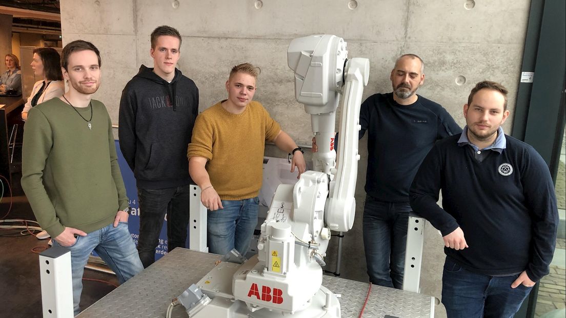 Studenten en hun docent bij de robot van ABB