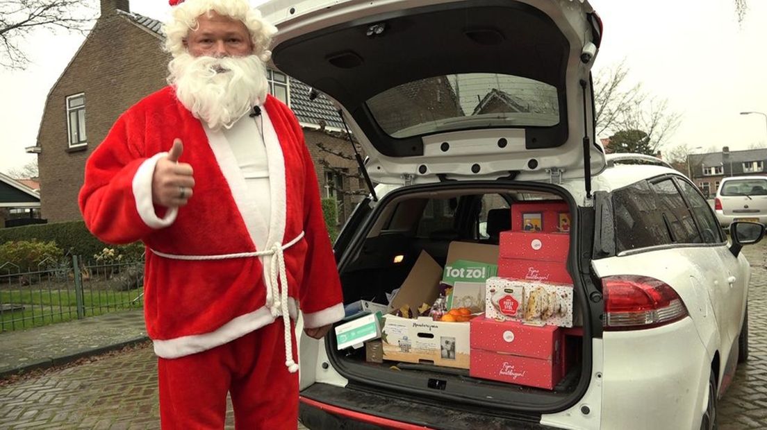 Frederik Bennis van Ouderen Gelderland met een auto vol kerstpakketten voor ouderen in Tiel.