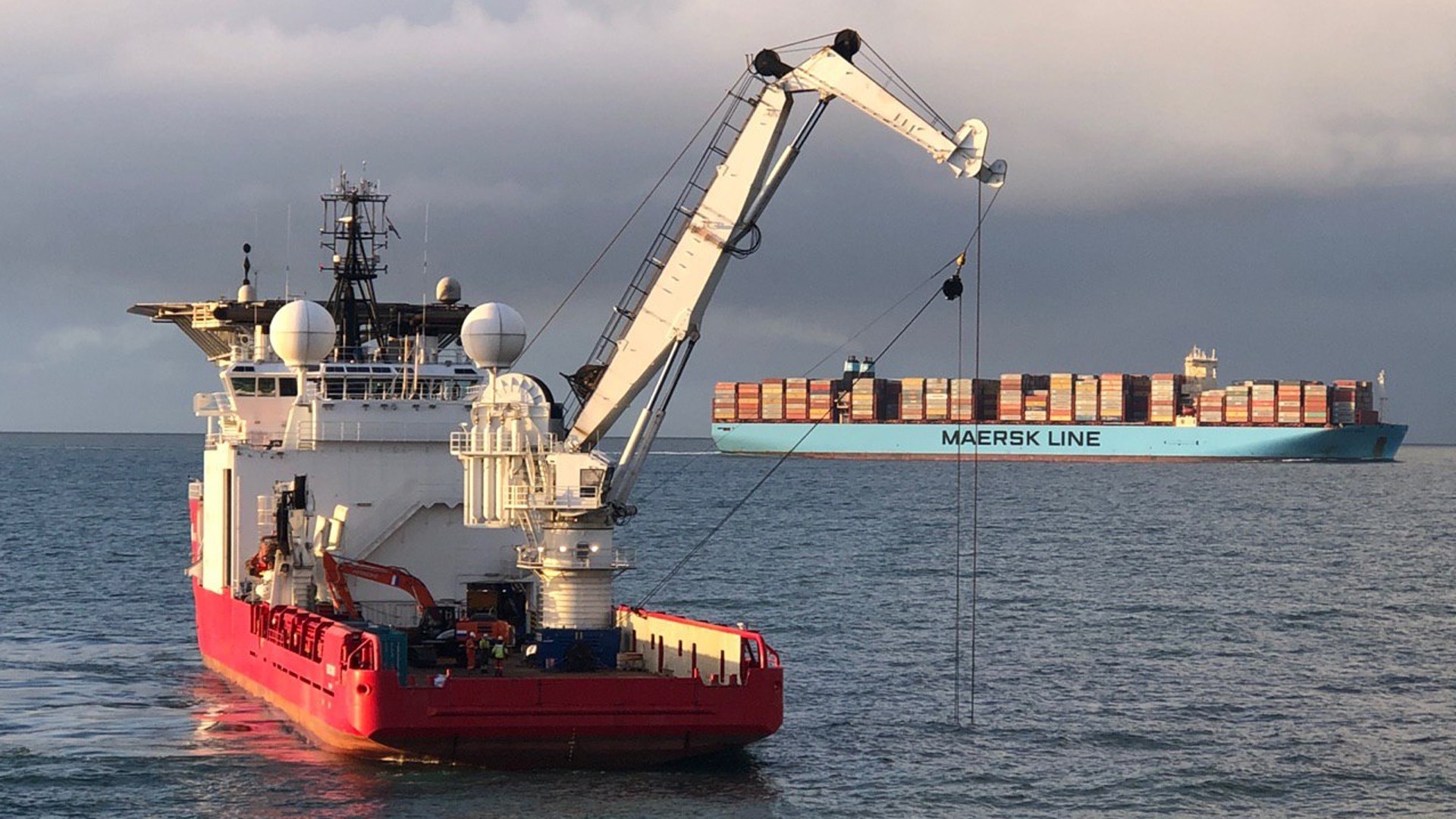 Een bergingsschip in actie, met op de achtergrond een containerschip van rederij Maersk
