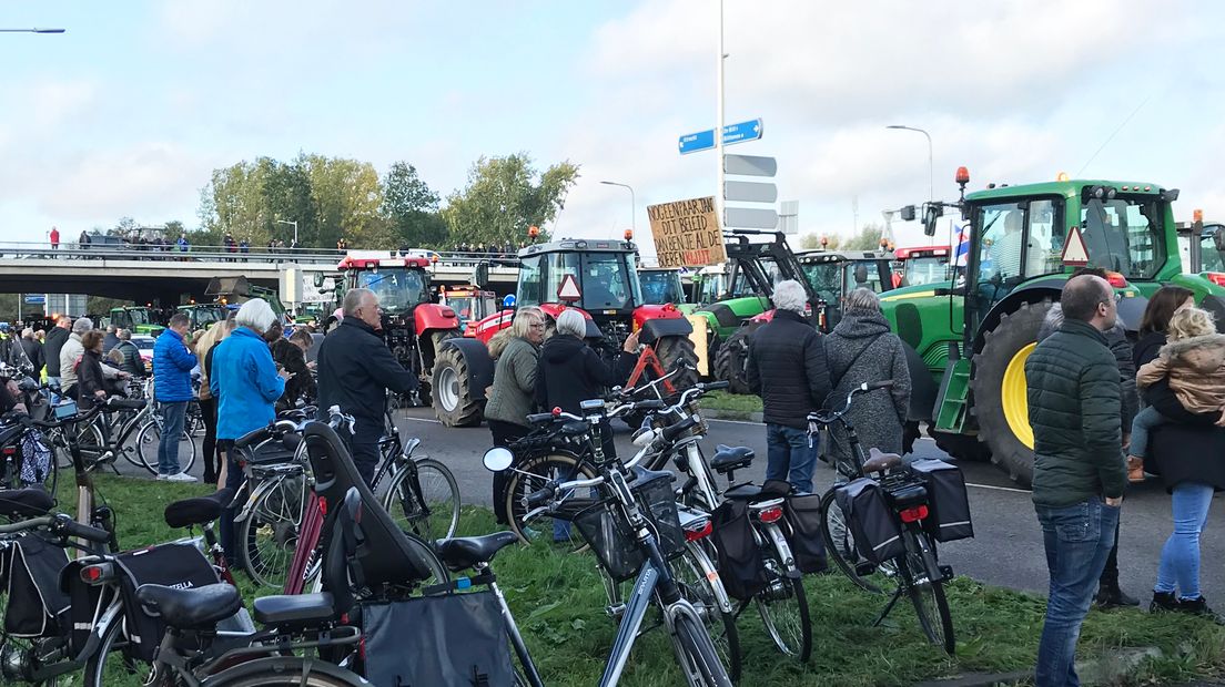 Voorbijgangers kijken toe naar het protest.