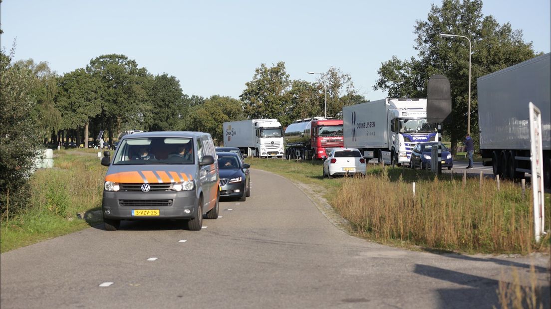 Lange file door gesloten spoorwegbomen bij overgang bij Mariënheem