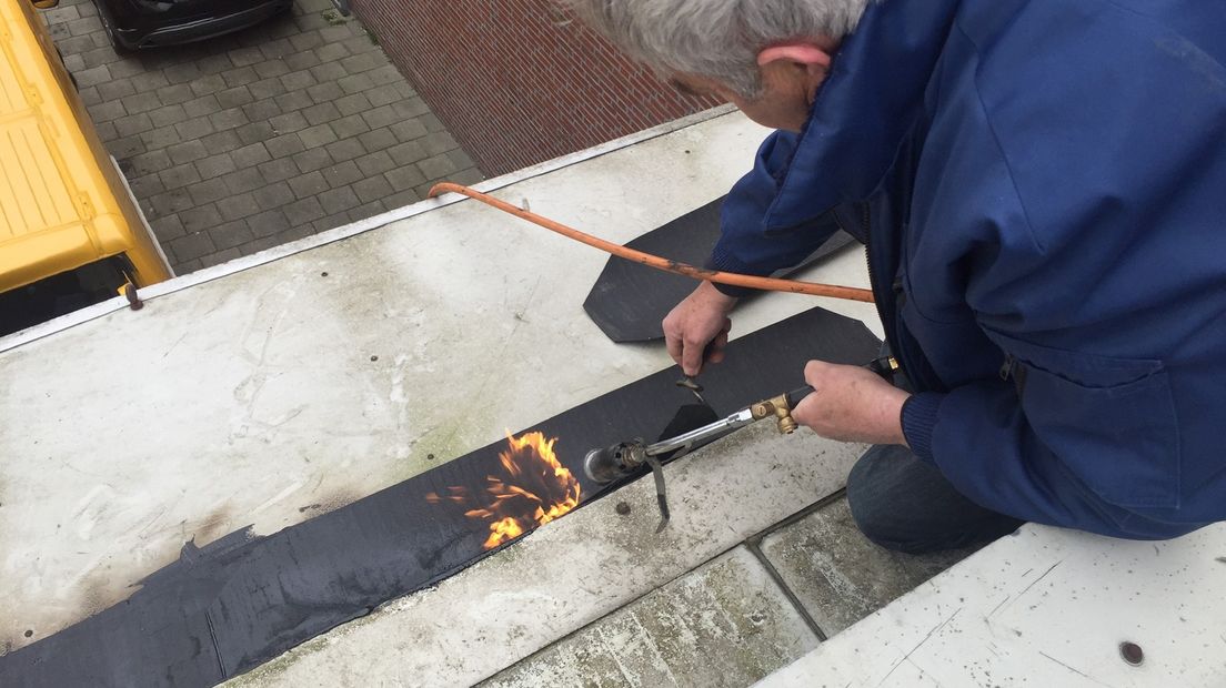 Medewerkers van de gemeente Delfzijl repareren een ander lek op het dak, even verderop.