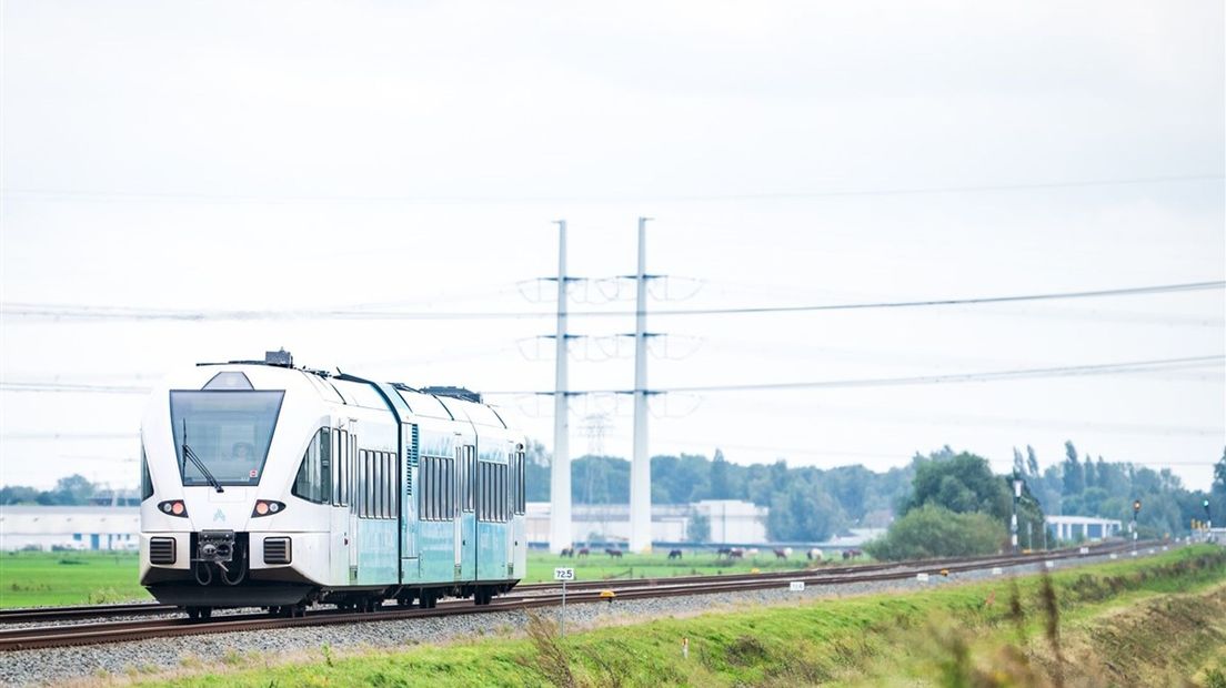 Een trein van Arriva passeert een spoorwegovergang.