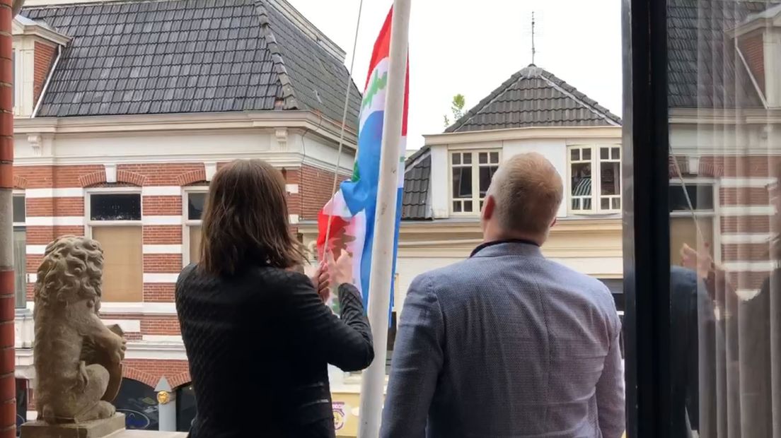 Burgemeester Cora-Yfke Sikkema van Oldambt en bedenker Mark van Esveld hijsen de aardbevingsvlag
