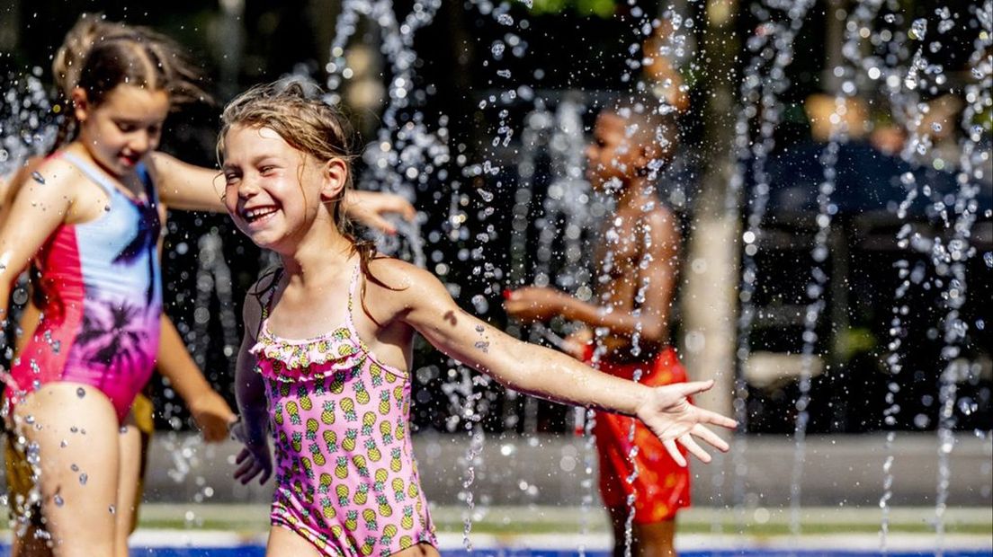 Kinderen zoeken verkoeling bij de fontein.