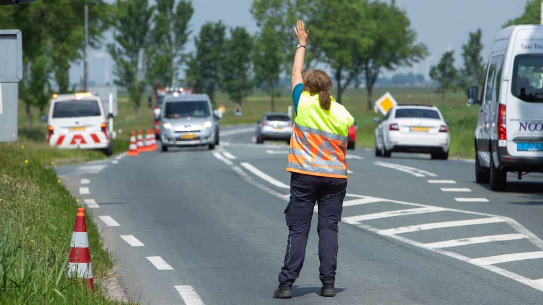 Een weginspecteur regelt het verkeer.