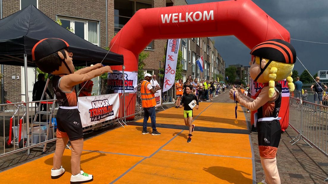 Na een eindsprint langs het publiek komen de deelnemers over de finish. Talkpoeder of niet, door de harde regen lopen ze te "soppen" in hun schoenen.