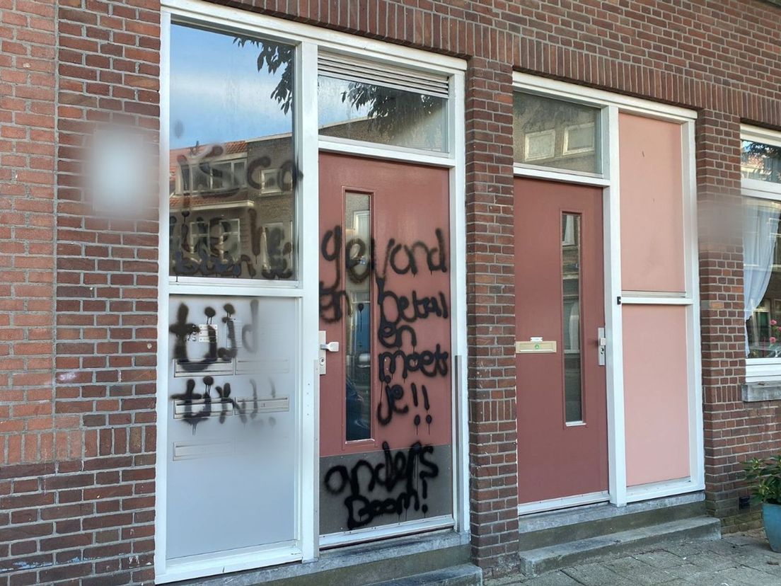 Op de voordeur van het portiek aan de Groepstraat is een dreigende boodschap gespoten