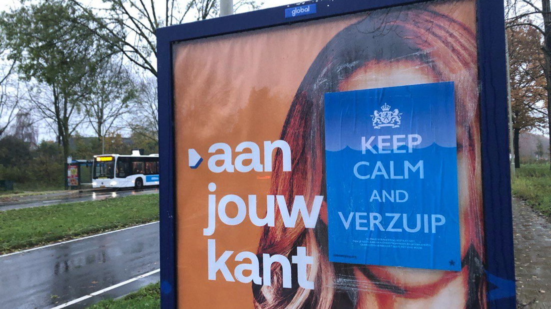 De poster geplakt op een VVD-verkiezingsposter.
