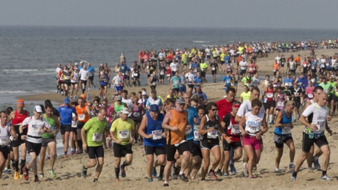 Deelnemers aan de Kustmarathon ploegen door het strand