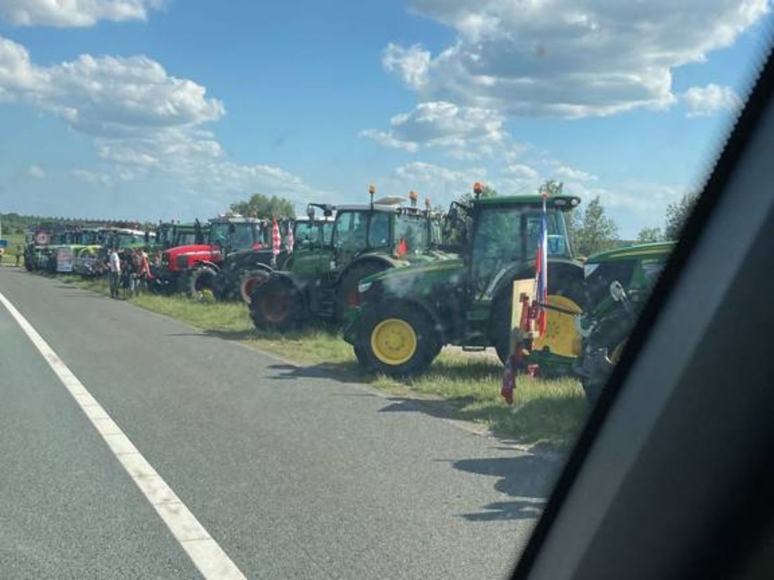 Een groep tractoren staat langs de snelweg in de berm