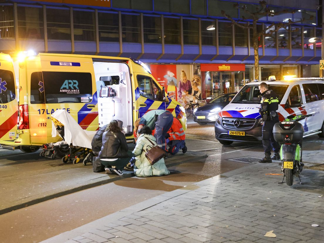 De voetganger wordt op de stoep aan de Karel Doormanstraat behandeld door het ambulancepersoneel.