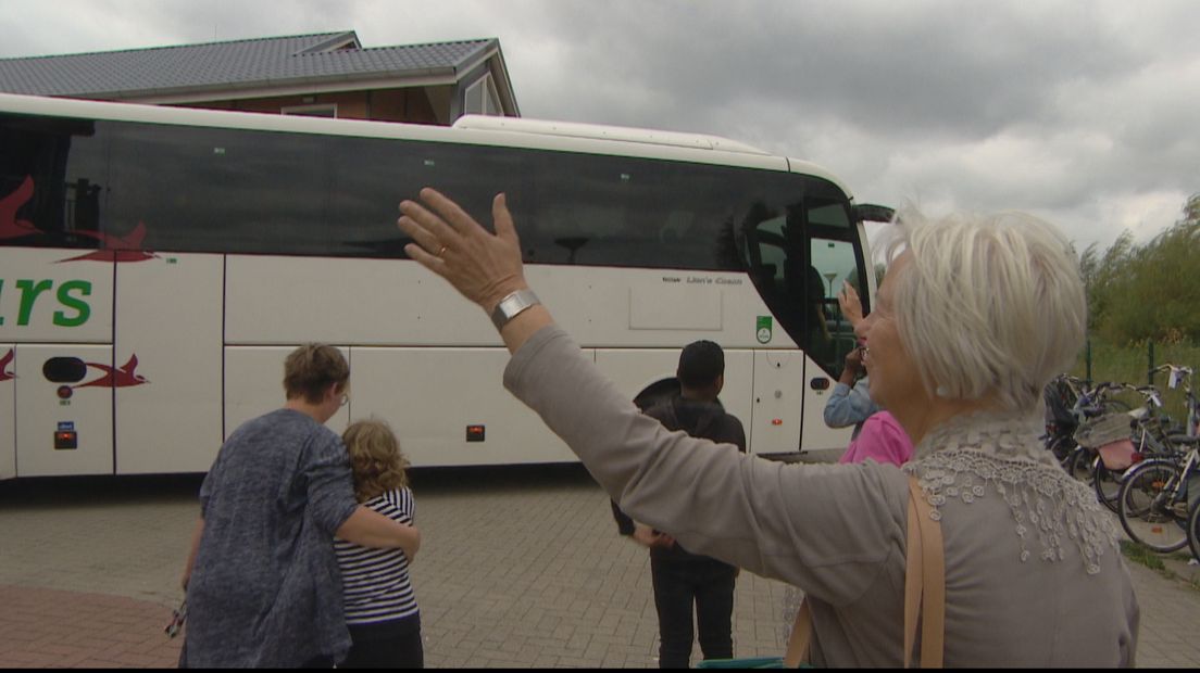 Toos de Visser zwaait de bus met vluchtelingen uit