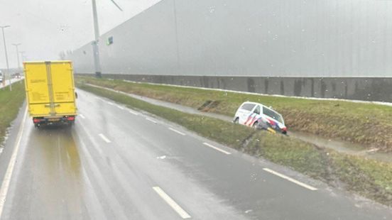 Politieauto schiet van de weg en belandt in sloot