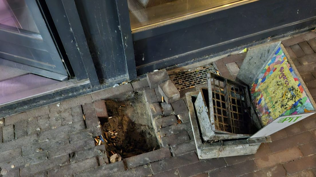 De asbaktegel voor de ingang van het winkelcentrum is uit de grond gehaald.