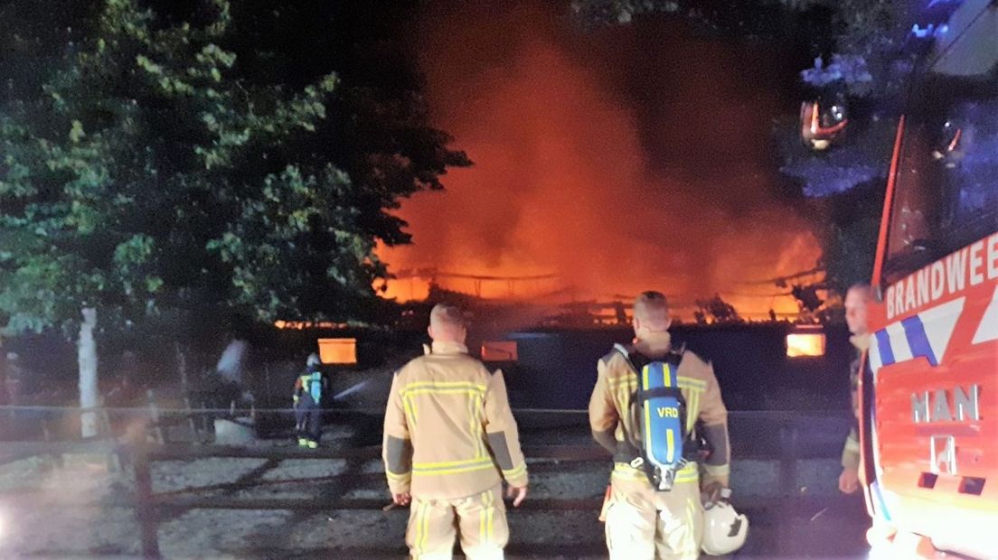 De vlammen slaan uit het dak van de schuur