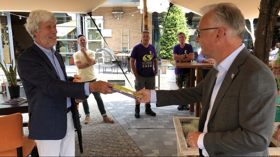 Wethouder Jacques van Loevezijn (r) neemt het wandelboekje in ontvangst van voorzitter Chris de Bont