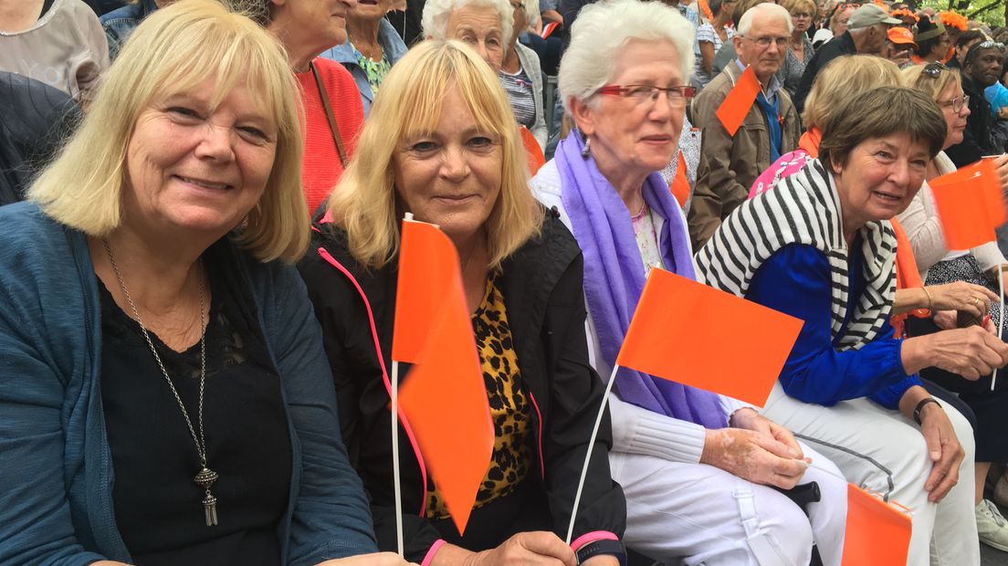 'Oranje boven,' zingen Hermien Timmer en Maria Peters uit volle borst op de blauwe tribune in Den Haag.  De Blauwe tribune aan de Lange Voorhout in Den Haag had beter oranjetribune kunnen heten, want het zit er vol met Gelderse koningshuisfans. Allemaal dragen ze wel een oranje hoedje, oranje sjaal of zwaaien met een oranje vlaggetje. Hermien en Maria zijn zussen. Ze wonen in Doetinchem en Vorden, maar de lange reistijd naar Den Haag kon hen vandaag niet tegen houden: 'Wij willen Willem-Alexander en Maxima zien,' klinkt het.