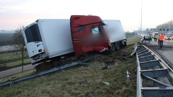 Vrachtwagen rijdt door vangrail op snelweg na aanrijding met andere auto, urenlange afsluiting. Vrachtwagen rijdt door vangrail op snelweg na aanrijding met andere auto, urenlange afsluiting.