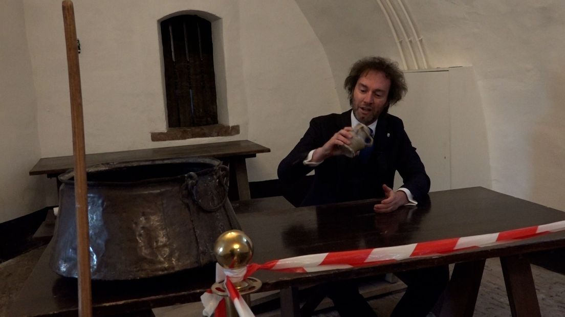 Ridder René bekijkt een middeleeuwse bierkan.