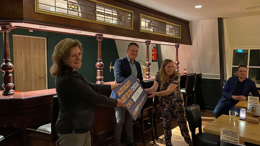 Tina Moes overhandigt de cheque aan wethouder Jan Broekema en Marieke Dufour van het goede doel