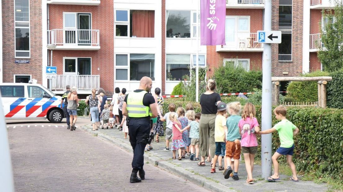 De politie begeleidt de kinderen en hun leidsters naar een andere plek