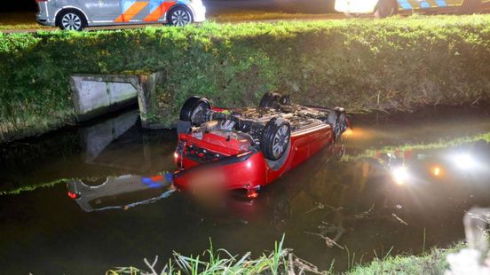 Auto op de kop in sloot naast dijk