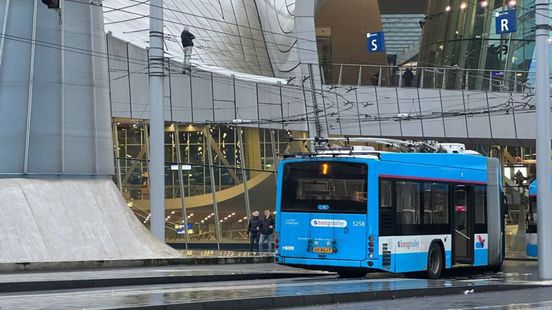Man staat op bovenleiding van trolleybus, Stationsplein Arnhem afgezet