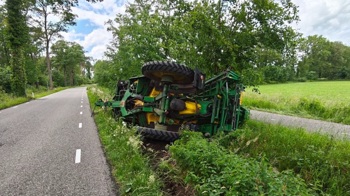 Tractor met veldspuit kantelt, belandt in de berm