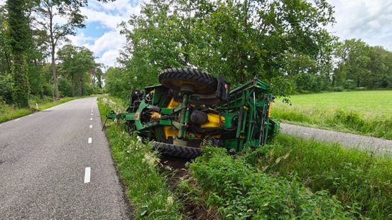 Tractor met veldspuit kantelt, belandt in de berm