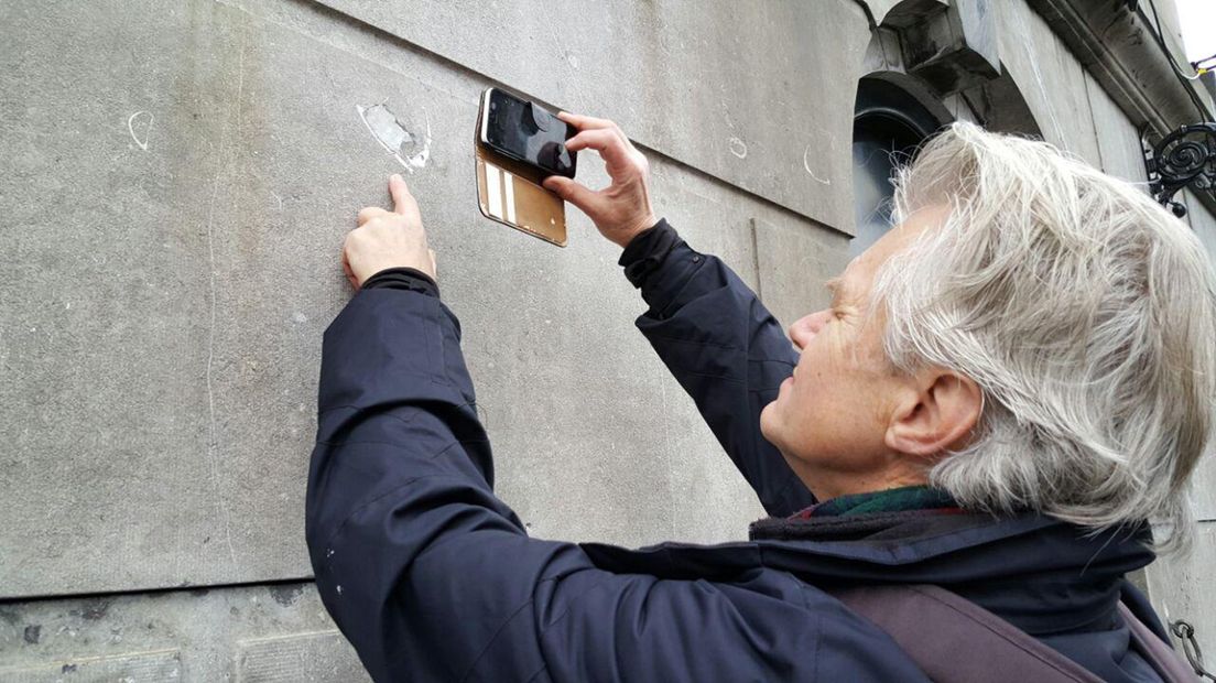 Jelle Reumer maakt een foto van een fossiel in de stenen van het Stadhuis