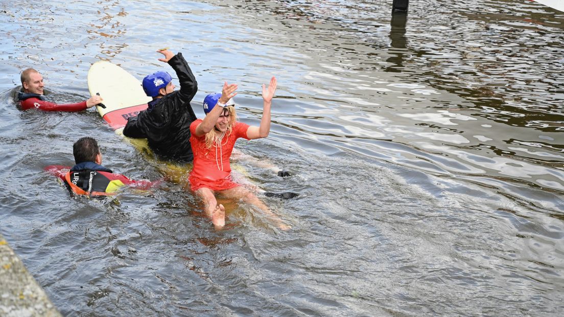Deelnemers die in het water vallen worden met surfplanken naar de kant gehaald