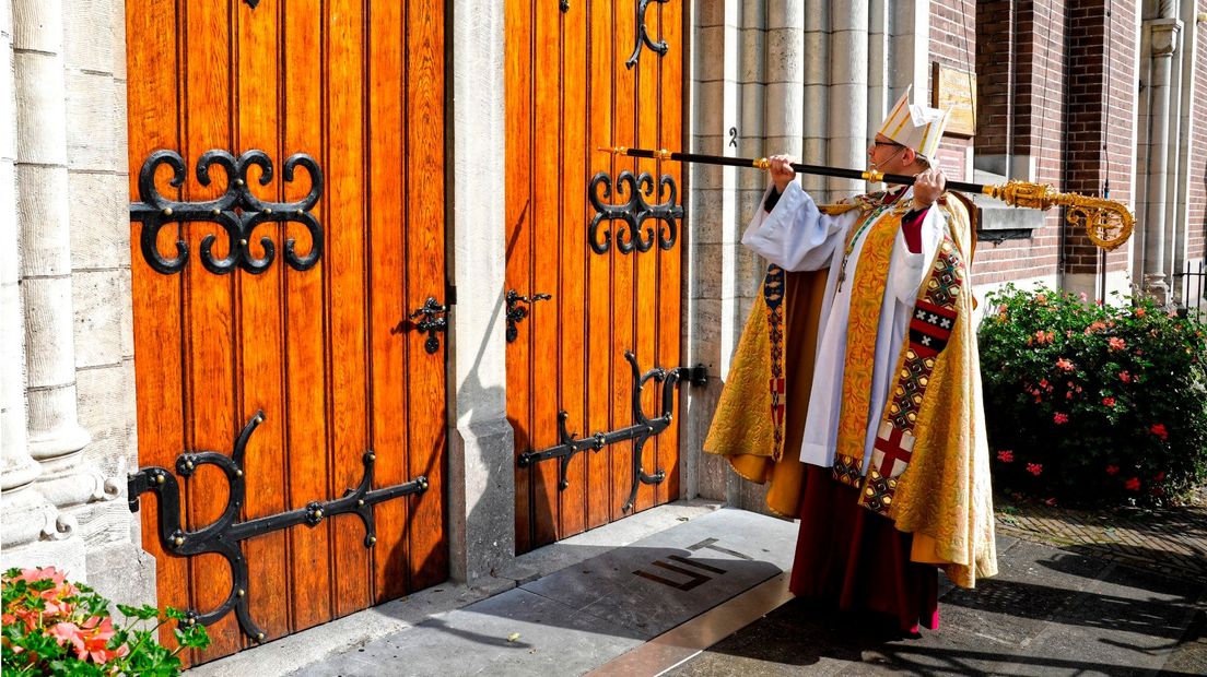 De bisschop klopt ceremonieel op de deur van de kathedraal.