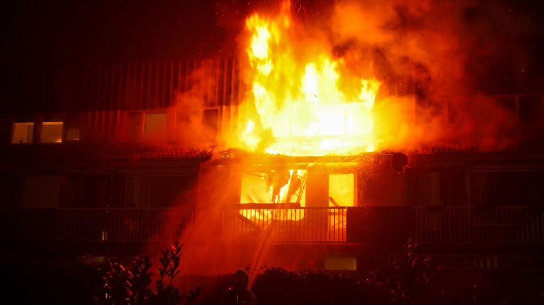 De vlammen slaan uit de woning.