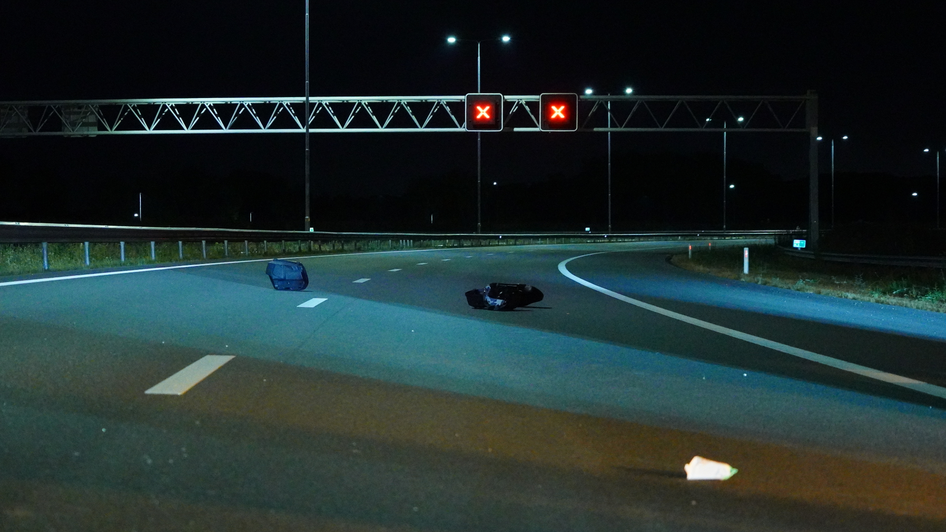 Brokstukken liggen verspreid op de weg.