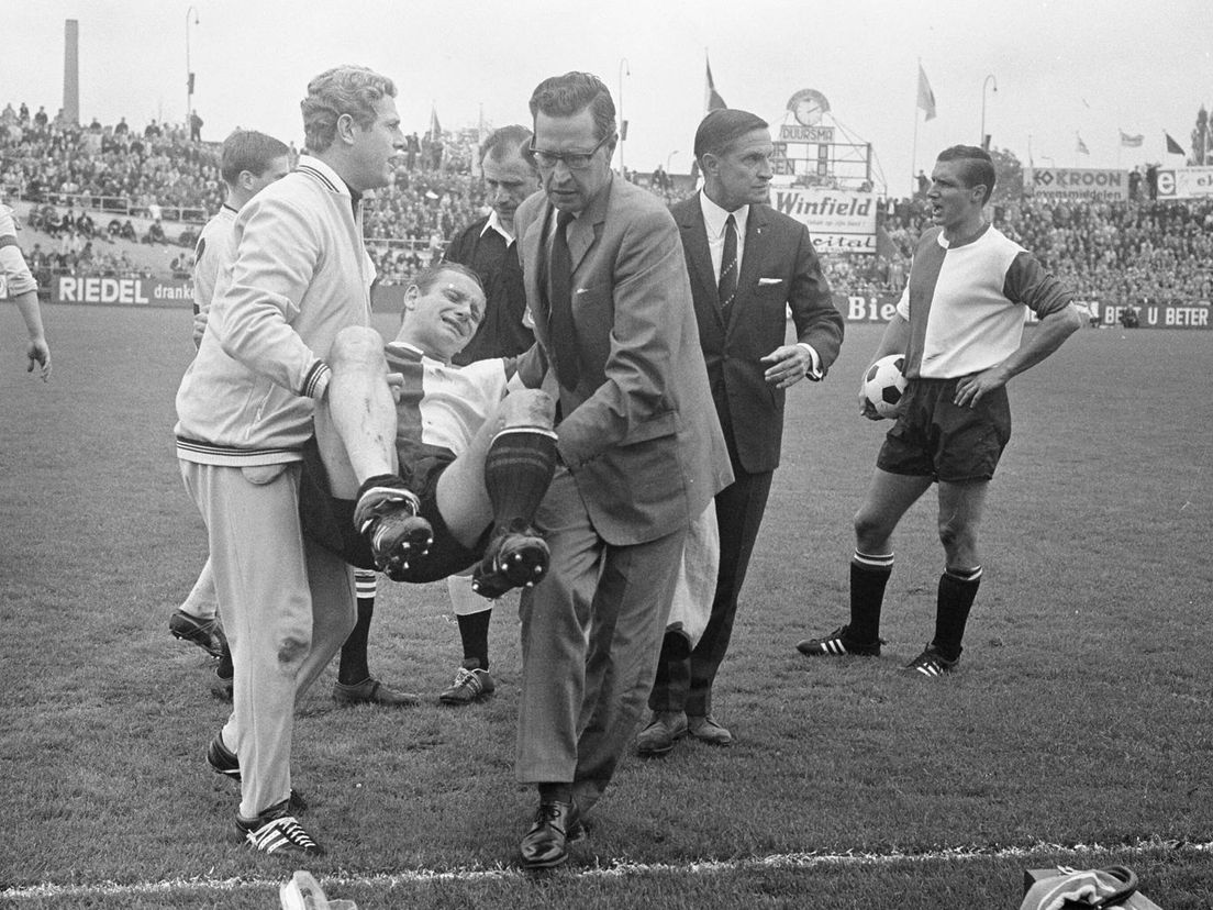 Feyenoord-speler Piet Fransen wordt buiten de lijnen gedragen in het uitduel met DOS, rechts trainer Willy Kment