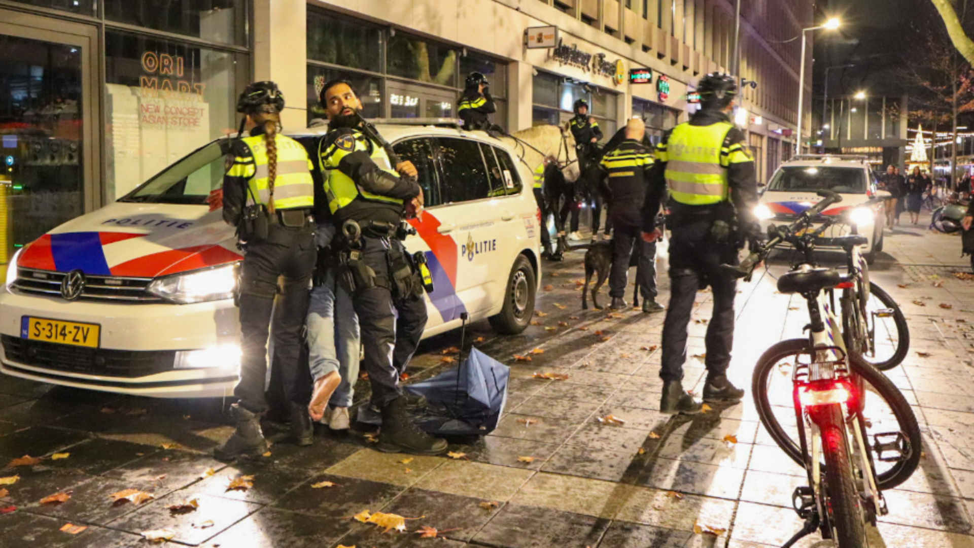 Twee agenten houden een man aan na de vechtpartij op het Stadhuisplein.