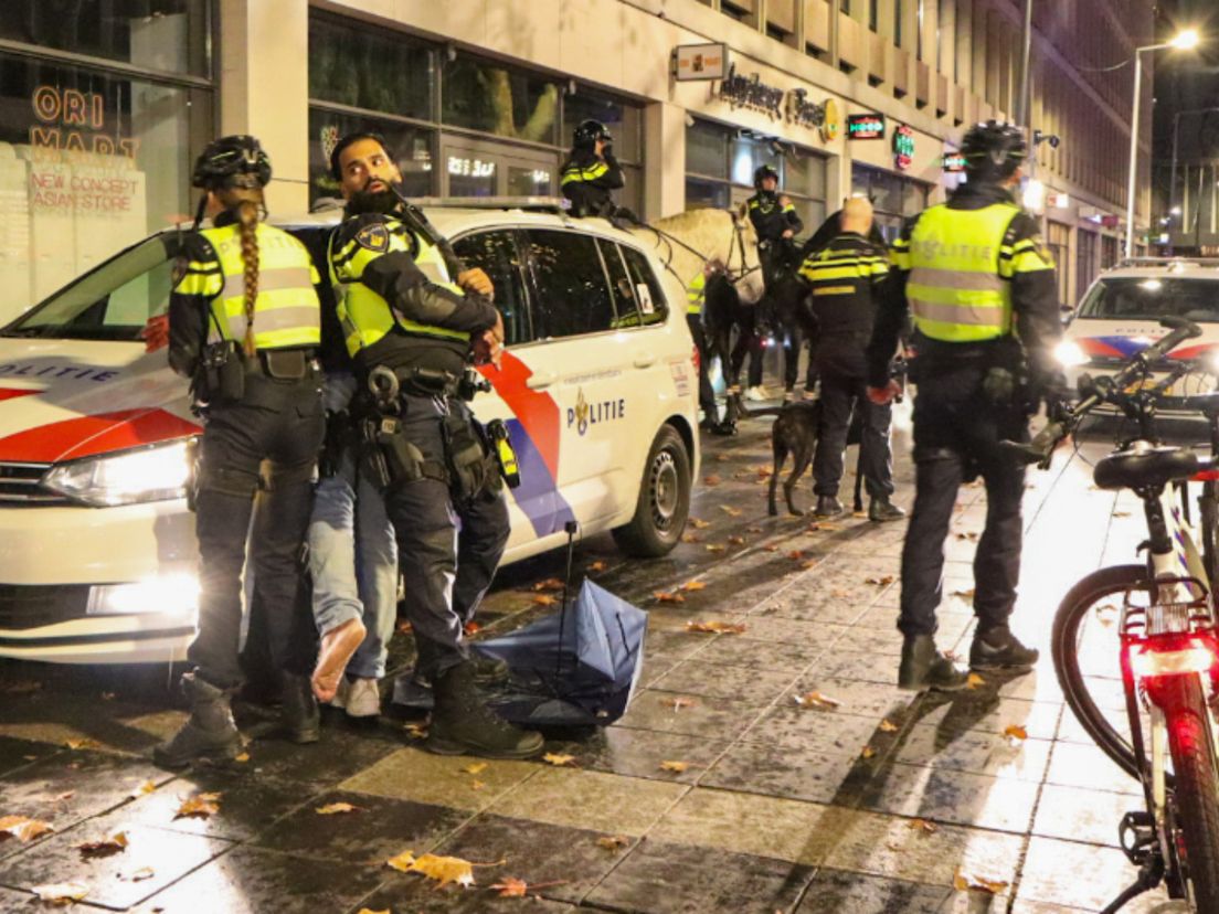 Twee agenten houden een man aan na de vechtpartij op het Stadhuisplein.