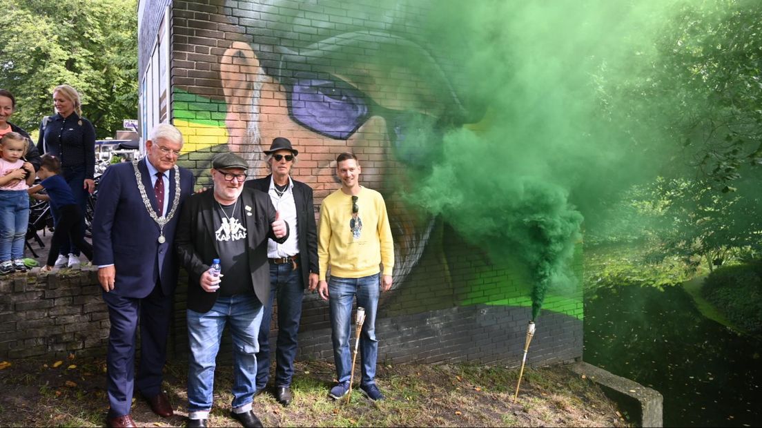 De muurschildering wordt onthuld met groene rook