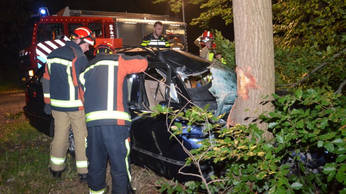 Hulpverleners bekijken de schade aan de auto.