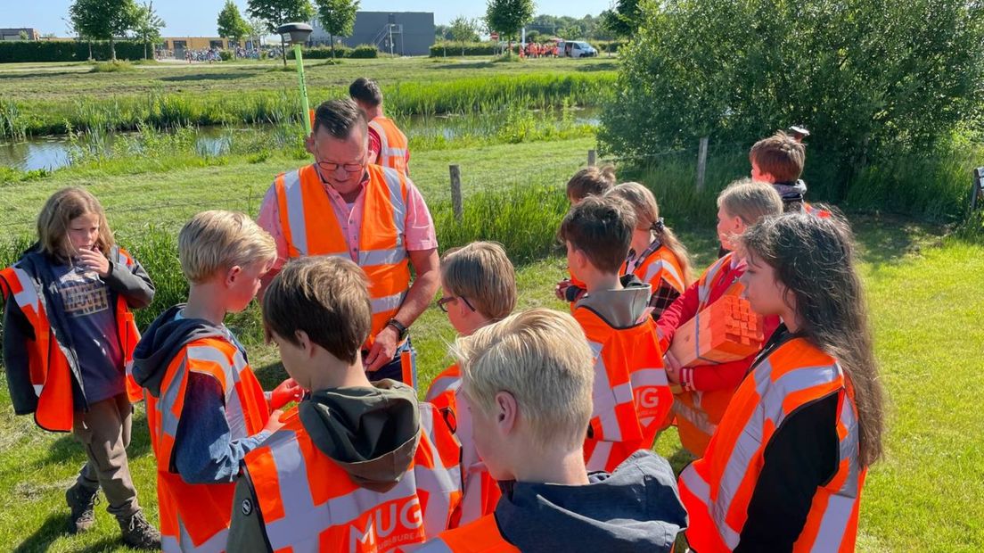 De kinderen krijgen uitleg van een landmeter