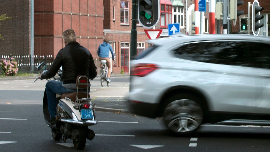 Een man op een scooter passeert een kruispunt