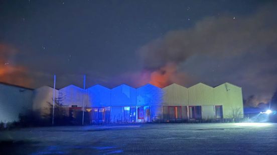 Enorme uitslaande brand in kas; brandweer met veel wagens aan het blussen