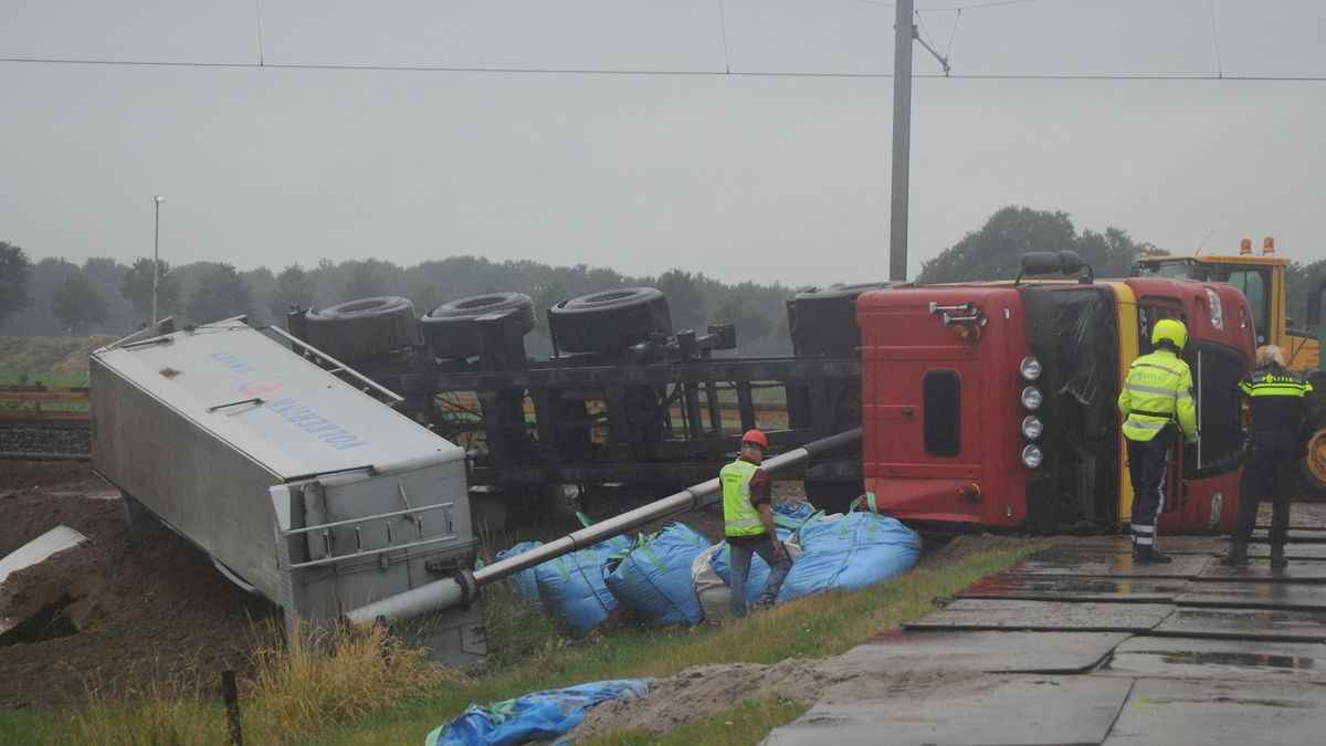 Truck met oplegger kantelt langs spoor in Holtheme