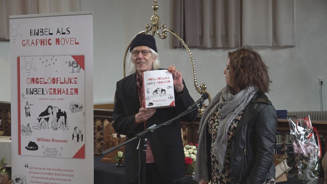 Zanger Rikkert Zuiderveld neemt het eerste exemplaar van de kinderbijbel in ontvangst