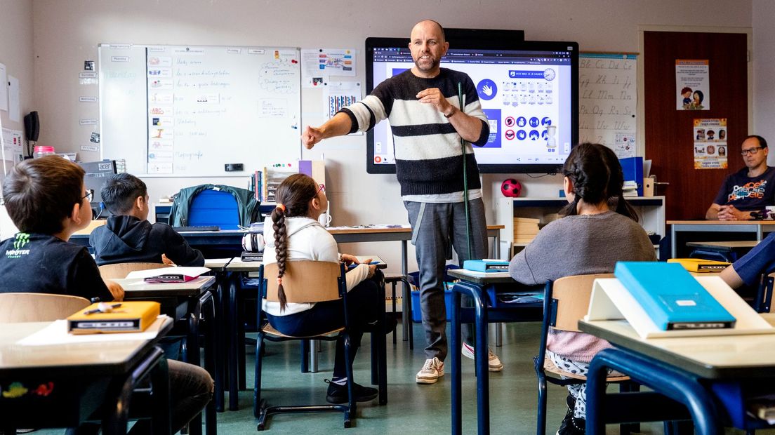 Een leraar laat in de klas aan basisschoolleerlingen zien wat de coronamaatregelen zijn (Rechten: ANP)