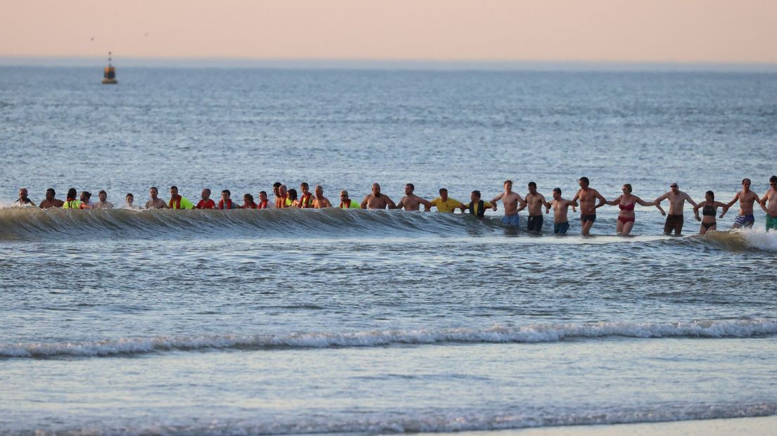 Strandgangers vormen een menselijke ketting in het water