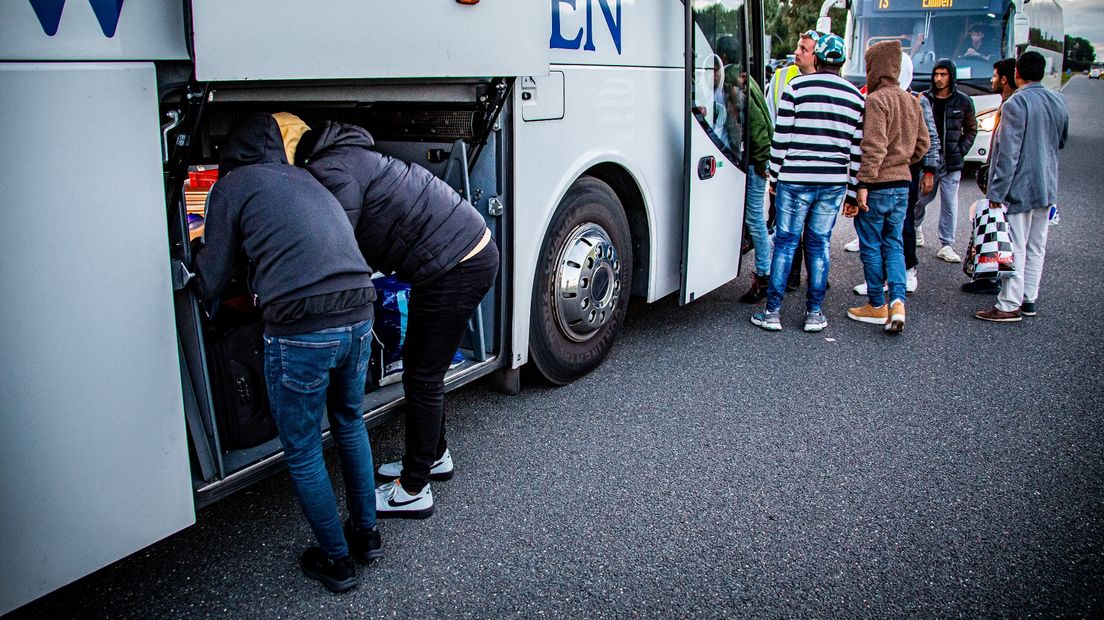 Asielzoekers stoppen hun spullen in een bus bij Ter Apel (archief)